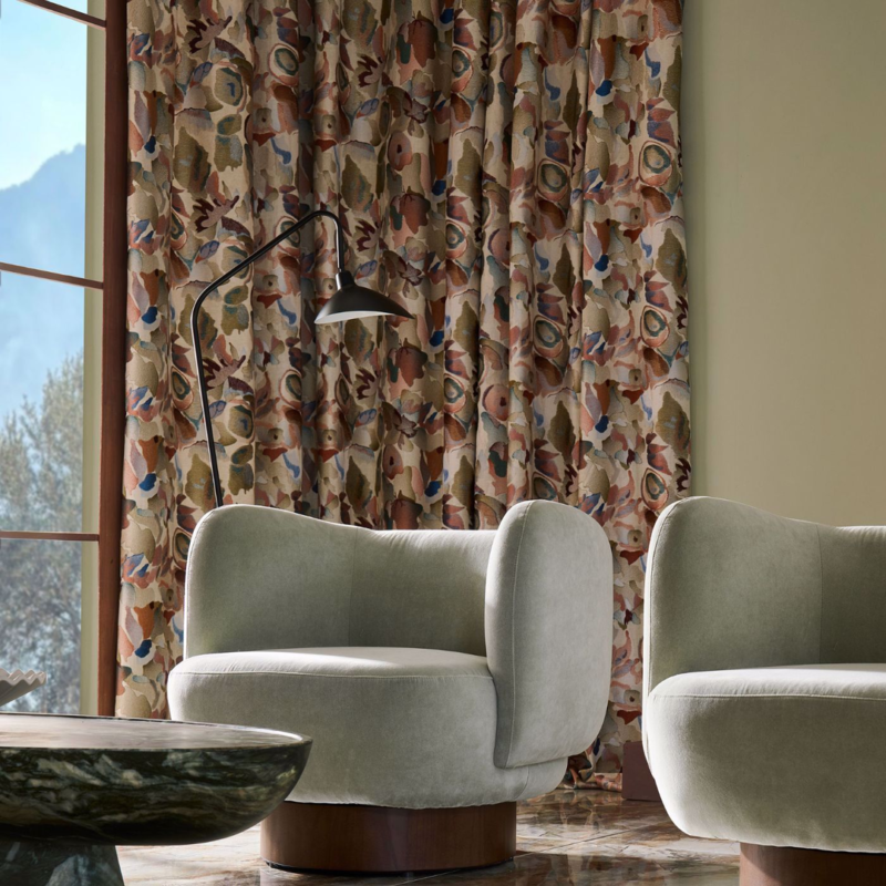 Harlequin Signature printed curtains behind two velvet armchairs