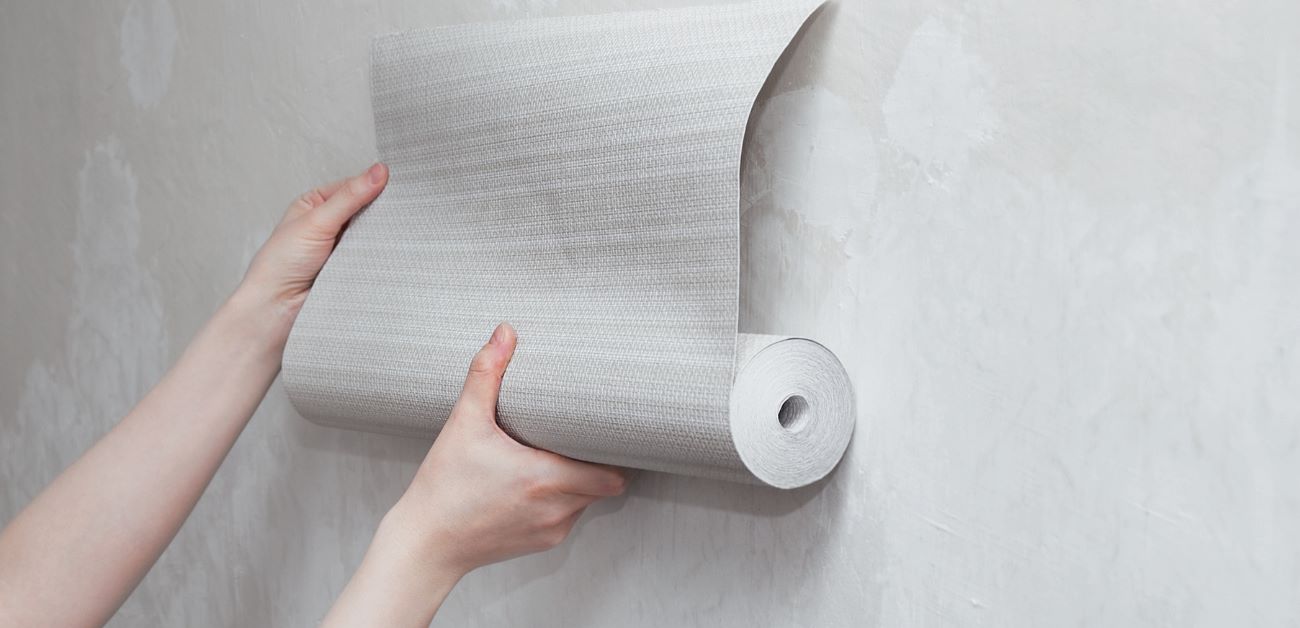 Hands installing wallpaper roll with precise technique for long-lasting results