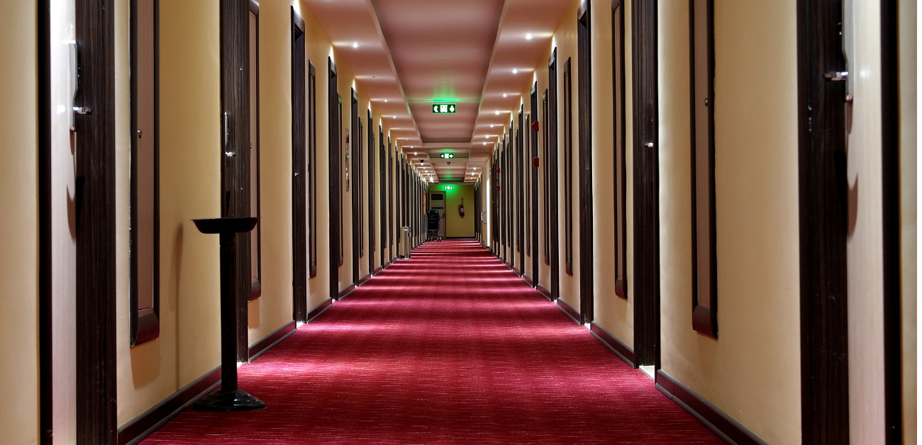 Long hotel hallway featuring heavy-duty carpet for guest comfort and wear resistance